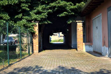 Güneşli bir günde, bir köyün parkında, ağaçların altında kısmen uzanan patika.