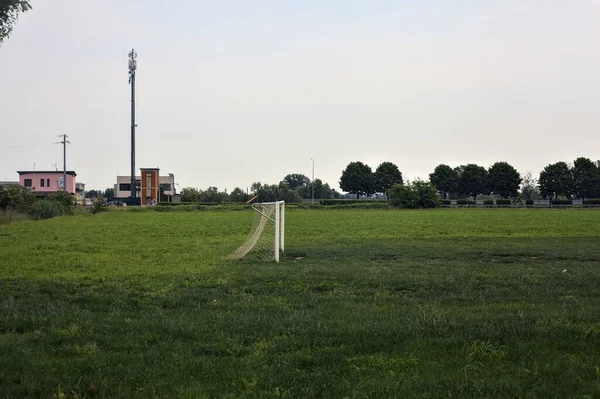 Soccer field with goal in a field and a road in the distance on a cloudy day in the italian countryside