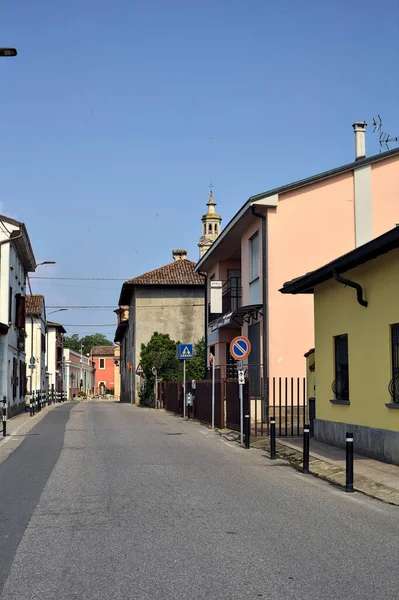 Road bordered by houses with a church at the end of it on a sunny day in a village in the italian countryside