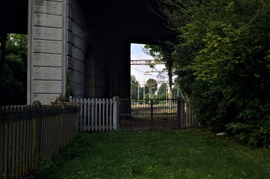 İtalya 'da gün batımında beton bir köprünün altından geçen bir parktaki tren yolu.