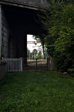 İtalya 'da gün batımında beton bir köprünün altından geçen bir parktaki tren yolu.