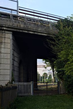 İtalya 'da gün batımında beton bir köprünün altından geçen bir parktaki tren yolu.