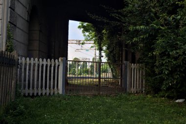 İtalya 'da gün batımında beton bir köprünün altından geçen bir parktaki tren yolu.
