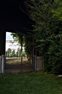 İtalya 'da gün batımında beton bir köprünün altından geçen bir parktaki tren yolu.