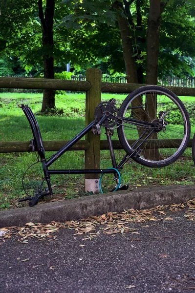 stock image Broken bike leaning on a wooden fence in a park at sunset