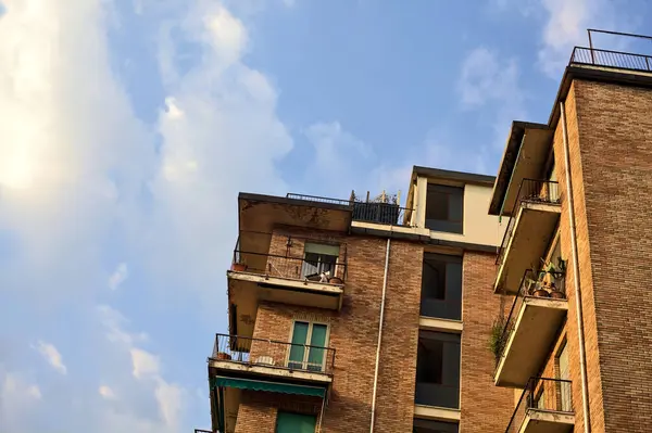 stock image Facade and roof of a building next to trees with a cloudy sunset sky as background