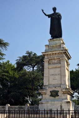 Güneşli bir günde parkta Publio Virgilio Marone anısına dikilmiş bir anıt.