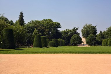 Güneşli bir günde parktaki patikaların arasında çitlerle çevrili