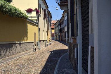 Güneşli bir günde İtalyan kasabasında kaldırımlı ve boş bir cadde