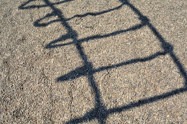 Schatten Einer Leiter Auf Kieselsteinen Gegossen — Stockfoto