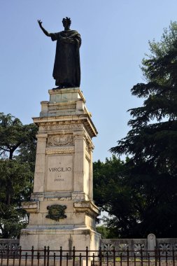 Güneşli bir günde parkta Publio Virgilio Marone anısına dikilmiş bir anıt.