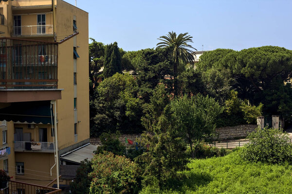Street next to a park and a condominium on a sunny day in an italian city