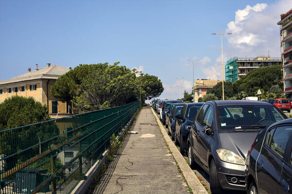 Pavement with parked cars by the edge of a highway in an italian city on a sunny day