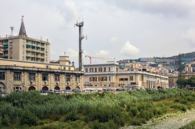 Bulutlu bir günde, bir İtalyan şehrinin ortasında binalarla çevrili nehir yatağı neredeyse bitkilerle kaplıydı.