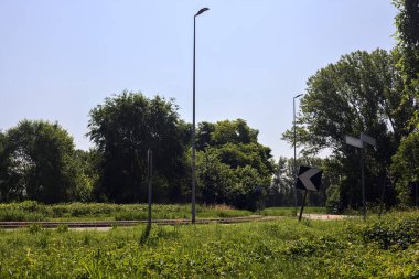 Yazın İtalya kırsalında ağaçlarla çevrili bir köy yolunda viraj