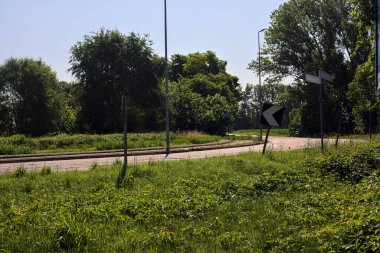 Yazın İtalya kırsalında ağaçlarla çevrili bir köy yolunda viraj