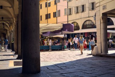 Güneşli bir günde, güneşli bir günde, gölgedeki bir verandadan insanların geçtiği bir meydan.