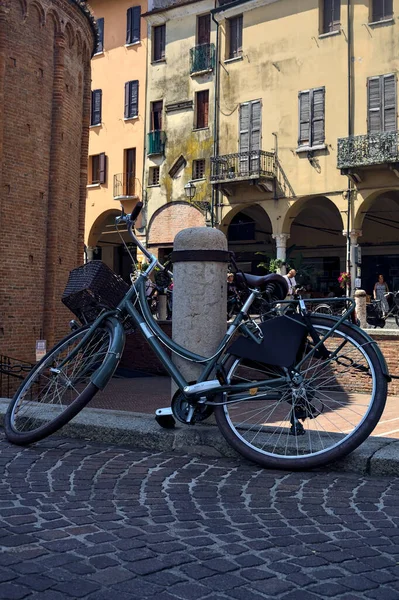 stock image Bike leaning on a pole in a square next to a street in an italian town