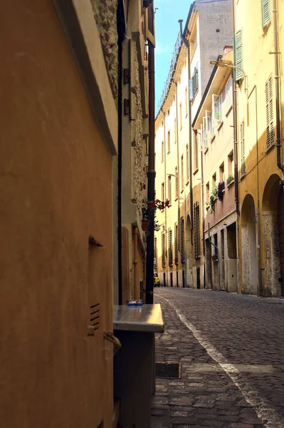 在阳光明媚的日子里 在意大利小镇上的一条狭窄的鹅卵石街道和一条木制长椅 — 图库照片