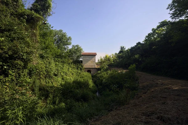 在意大利乡村的一条土路旁边的一个公园的水沟上建造了一座建筑 — 图库照片