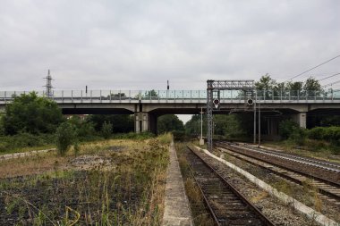 İtalya kırsalında bulutlu bir günde küçük bir viyadük altından geçen demiryolu rayların kenarından görülüyor.