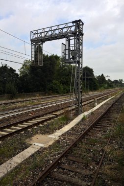 İtalya kırsalında bulutlu bir günde tren yolu ve bir istasyon.