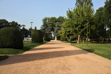 Gün batımında bir parkta bir çeşmeye giden yol.