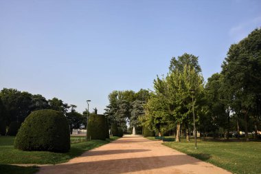 Gün batımında bir parkta bir çeşmeye giden yol.