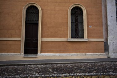 Günbatımında bir İtalyan kasabasında, kaldırımlı bir caddede, ahşap kapılar.