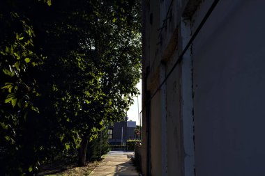 Gün batımında köy yolunda yaya geçidine çıkan bir binanın yanındaki parktaki çakıl yolu.