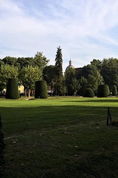 日落时分 意大利小镇上的一个有树木和教堂圆顶的公园里的草坪 — 图库照片