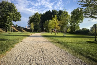 İtalya 'da gün batımında setin yanındaki ağaçların olduğu bir parkta yol.