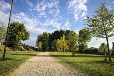İtalya 'da gün batımında setin yanındaki ağaçların olduğu bir parkta yol.