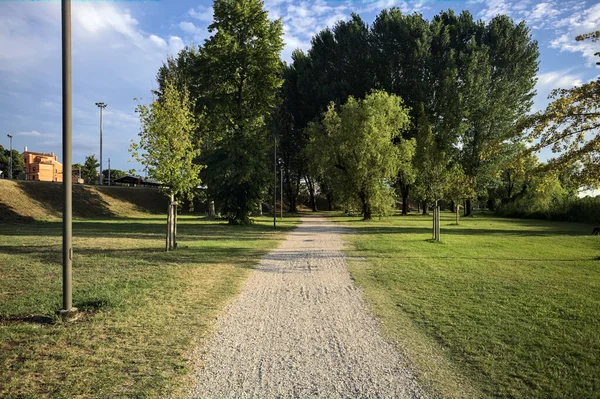 İtalya 'da gün batımında setin yanındaki ağaçların olduğu bir parkta yol.