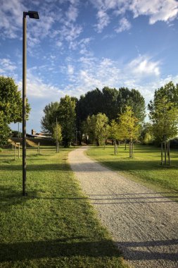 İtalya 'da gün batımında setin yanındaki ağaçların olduğu bir parkta yol.