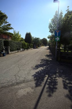 Güneşli bir günde İtalyan köyünün duvarlarında çitlerle ve bahçelerle çevrili bir sokak.