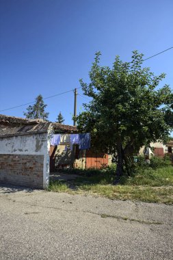 Güneşli bir günde garajların yanında kurutmak için asılacak elbiseleri ve ağaçları olan bir İtalyan köyünün arka bahçesinde.