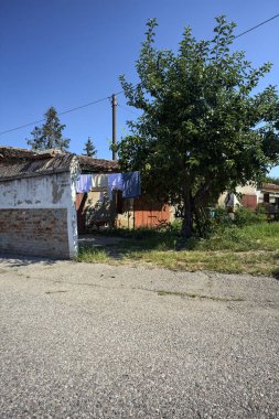 Güneşli bir günde garajların yanında kurutmak için asılacak elbiseleri ve ağaçları olan bir İtalyan köyünün arka bahçesinde.