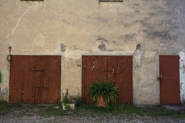 Önlerindeki çakıllı yoldan görünen bir binanın kırmızı garaj kapıları.