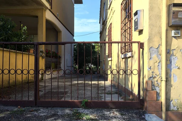 Kırsal kesimdeki bir İtalyan köyünün iki evi arasındaki giriş yolu gündüz vakti bir kapı tarafından kapatılmış.