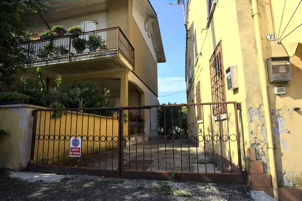 Kırsal kesimdeki bir İtalyan köyünün iki evi arasındaki giriş yolu gündüz vakti bir kapı tarafından kapatılmış.