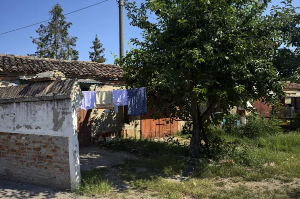 Güneşli bir günde garajların yanında kurutmak için asılacak elbiseleri ve ağaçları olan bir İtalyan köyünün arka bahçesinde.