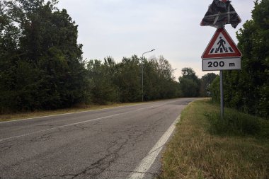 Yağmur yağmadan önce bulutlu bir günde ağaçlarla çevrili bir köy yolu.