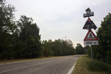 Yağmur yağmadan önce bulutlu bir günde ağaçlarla çevrili bir köy yolu.