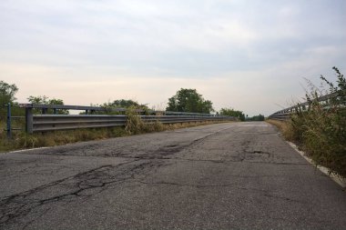 İtalya kırsalında yağmur yağmadan önce bulutlu bir günde kaldırım ve parmaklıklarla dolu bir köprü.