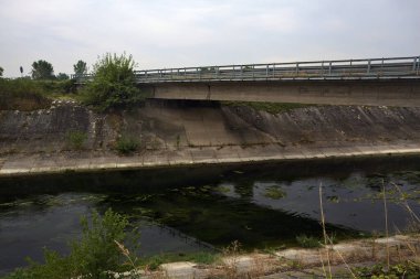 Yağmur yağmadan önce bulutlu bir günde İtalya kırsalında bir eğlence kanalı üzerinde köprü