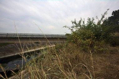 Yağmur yağmadan önce bulutlu bir günde İtalya kırsalında bir eğlence kanalı üzerinde köprü