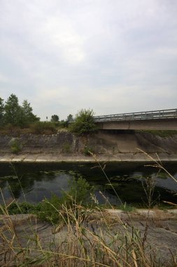Yağmur yağmadan önce bulutlu bir günde İtalya kırsalında bir eğlence kanalı üzerinde köprü