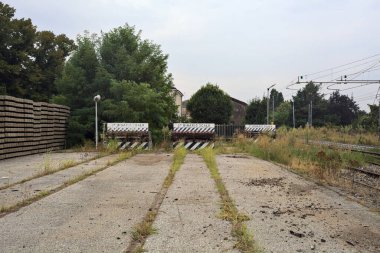 İtalya kırsalında bulutlu bir günde tren istasyonunun açıklığında üç çıkmaz yol.