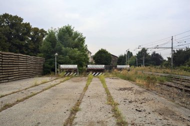 İtalya kırsalında bulutlu bir günde tren istasyonunun açıklığında üç çıkmaz yol.